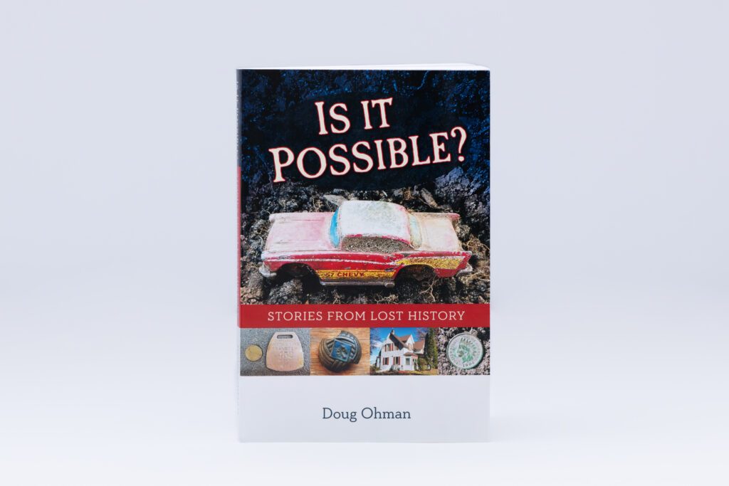 Softcover book 'Is It Possible? Stories from Lost History' by Doug Ohman featuring glossy laminated cover with toy truck and other historical items against a dark starry background.