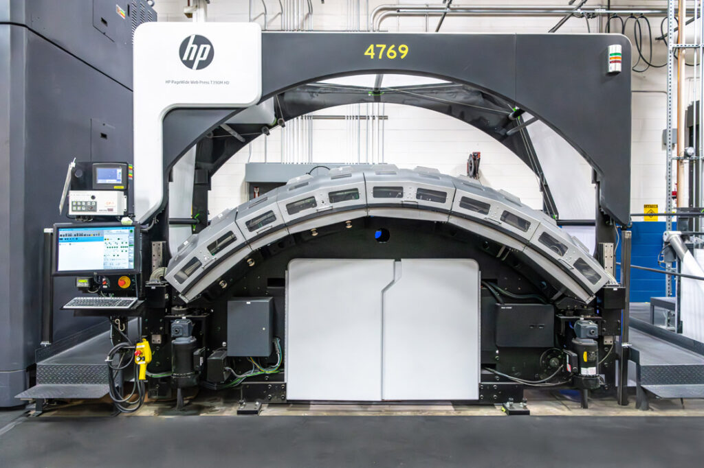 Front view of HP T360 mono digital printer with distinctive curved paper delivery arch and white paper roll storage cabinet beneath